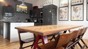 Una cocina moderna con una mesa y sillas de madera, una lámpara colgante e ilustraciones enmarcadas en la pared.