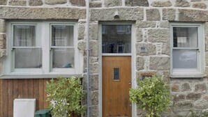 Un edificio de piedra con dos ventanas y una puerta de madera.