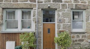 Un edificio de piedra con dos ventanas y una puerta de madera.