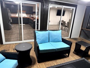 Un'area patio con un divano in rattan, un tavolino rotondo e un tavolo da pranzo.