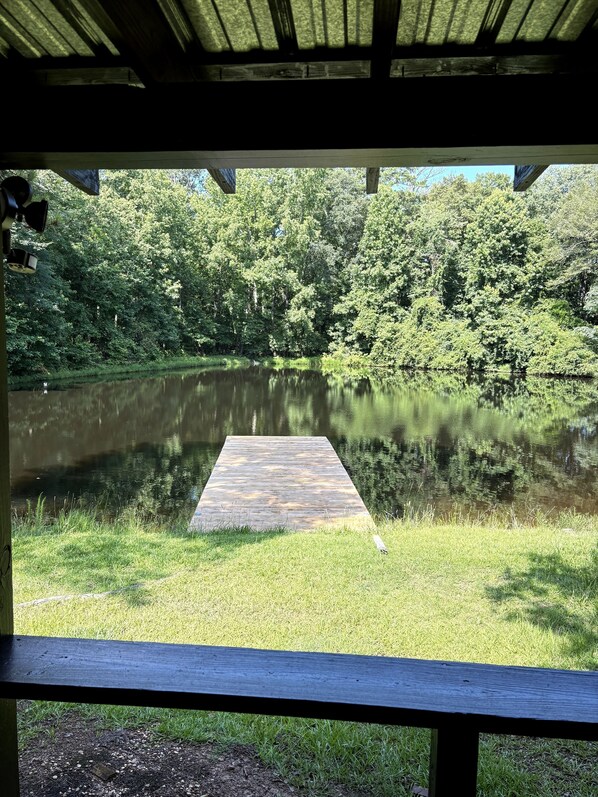 A wooden dock extending into a calm lake surrounded by lush greenery.