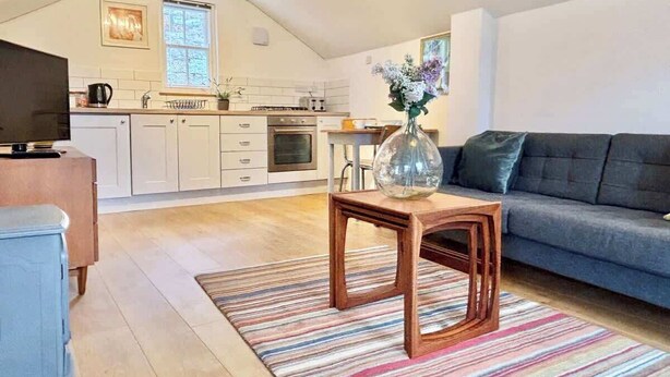 A modern living room with a sofa, a coffee table, and a TV. - The Coach House, Penzance- Cosy Nook for 2 (Penzance)