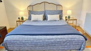 A bed with a wooden headboard, two bedside tables with lamps, and a patterned bedspread. - The Coach House, Penzance- Cosy Nook for 2 (Penzance)