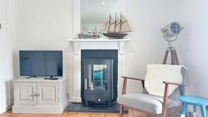 Ein Wohnzimmer mit Kamin, Fernseher, Sessel und Stehlampe.