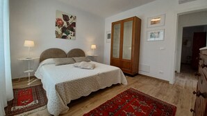 Un dormitorio con una cama, dos lámparas de noche, un armario y una alfombra roja con estampado.
