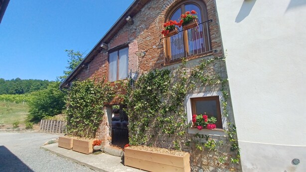 Una casa in mattoni rustica con un balcone, scale in legno e fioriere.