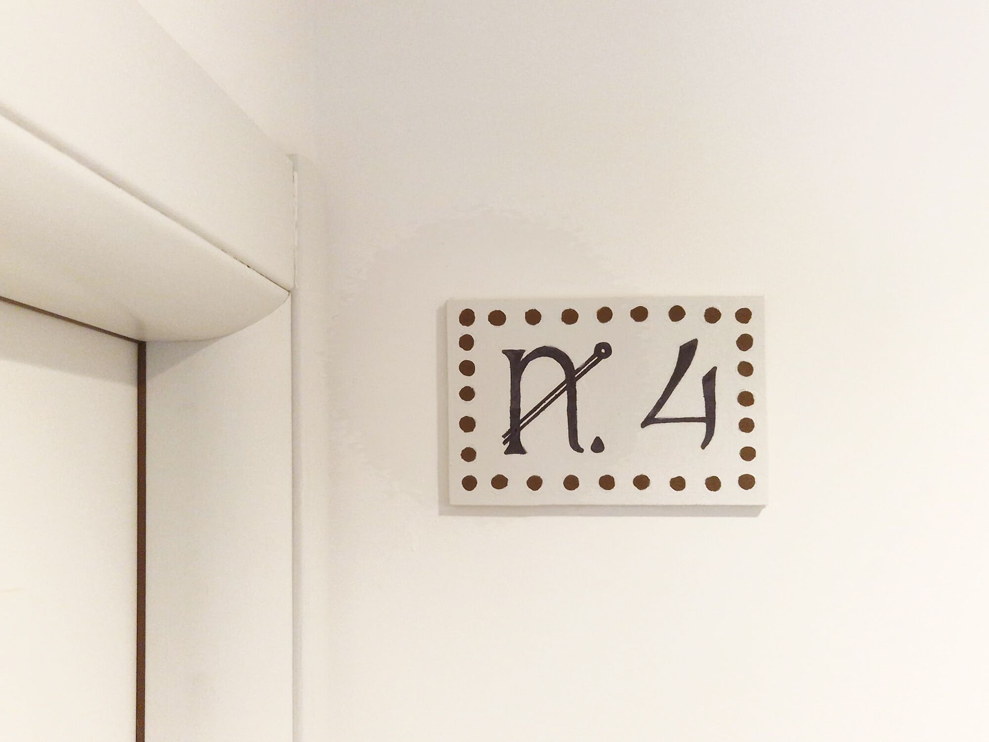 A wall-mounted sign with a decorative border and the number "4" in the center.