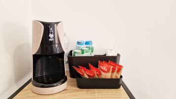 A coffee maker, two cartons of milk, and a tray of coffee pods on a table.