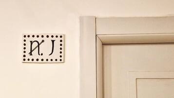 Una placa en la pared con las letras 'P.J.' y una puerta de diseño sencillo.