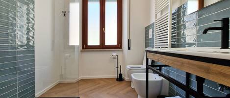 Un baño moderno con suelo de madera, un espejo grande y una ventana.
