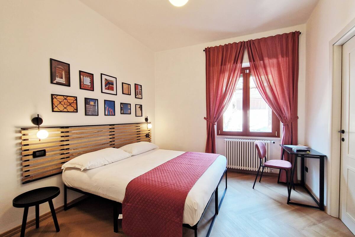 Une chambre à coucher avec un lit, un bureau, une chaise et un radiateur.
