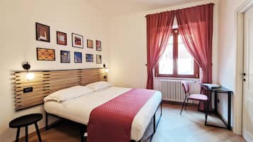 A bedroom with a bed, a desk, a chair, and a radiator.