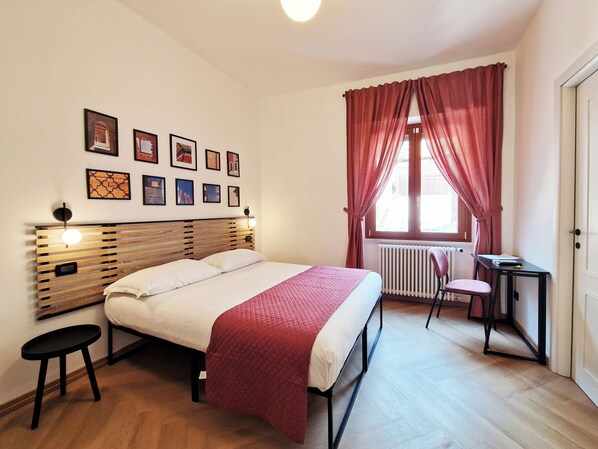 A bedroom with a bed, a desk, a chair, and a radiator.