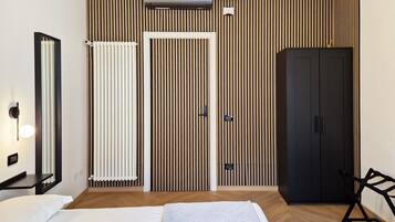 A modern hotel room with a bed, a wardrobe, a radiator, and a wall-mounted air conditioning unit.
