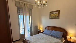 Una camera da letto con un letto, un lampadario, un quadro e una finestra con tende.
