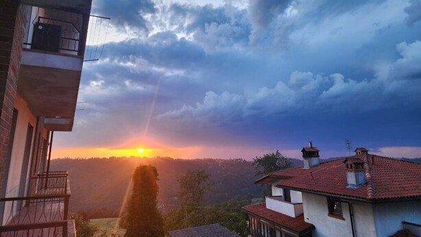 Un edificio con un balcone affacciato su un tramonto.