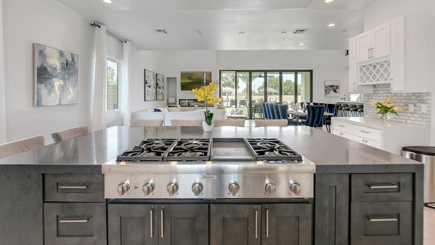 Cozinha moderna com ilha central, eletrodomésticos de aço inoxidável e muita luz natural proveniente de grandes janelas.