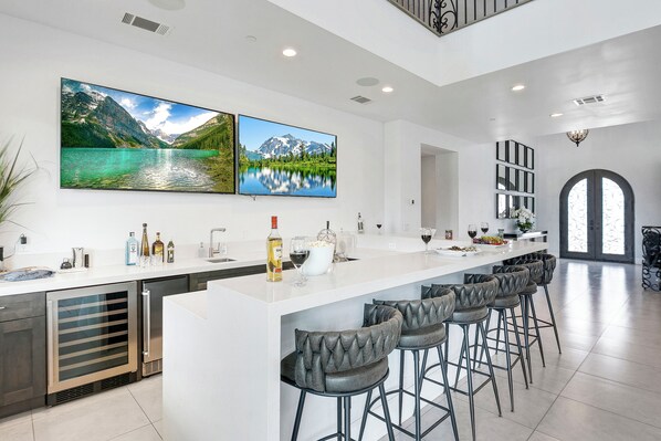 Une cuisine moderne dotée d’un grand îlot central, de tabourets de bar et de deux grands tableaux représentant des paysages.