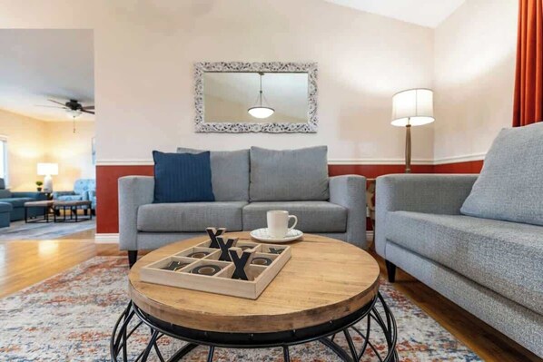 A living room with two sofas, a coffee table with a tray, a mirror, and a lamp.