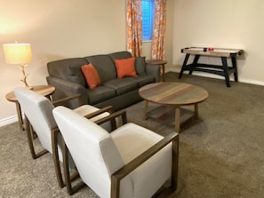 Living room with a sofa, two accent chairs, and mini air hockey