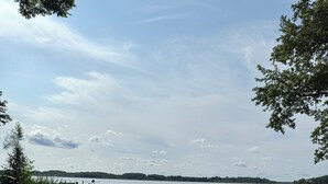 A grassy area with yoga mats and blocks, a dock, and a lake with a distant shoreline. - Seehotel Köllnitz (Storkow)