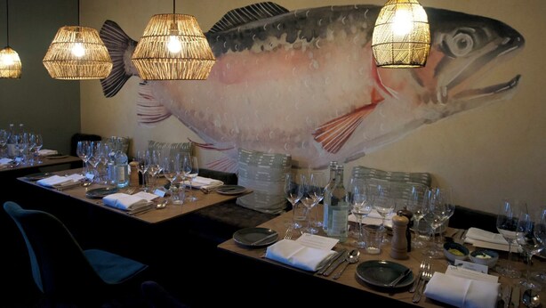A restaurant dining area with tables set for service, a large fish mural on the wall, and hanging wicker lamps. - Seehotel Köllnitz (Storkow)