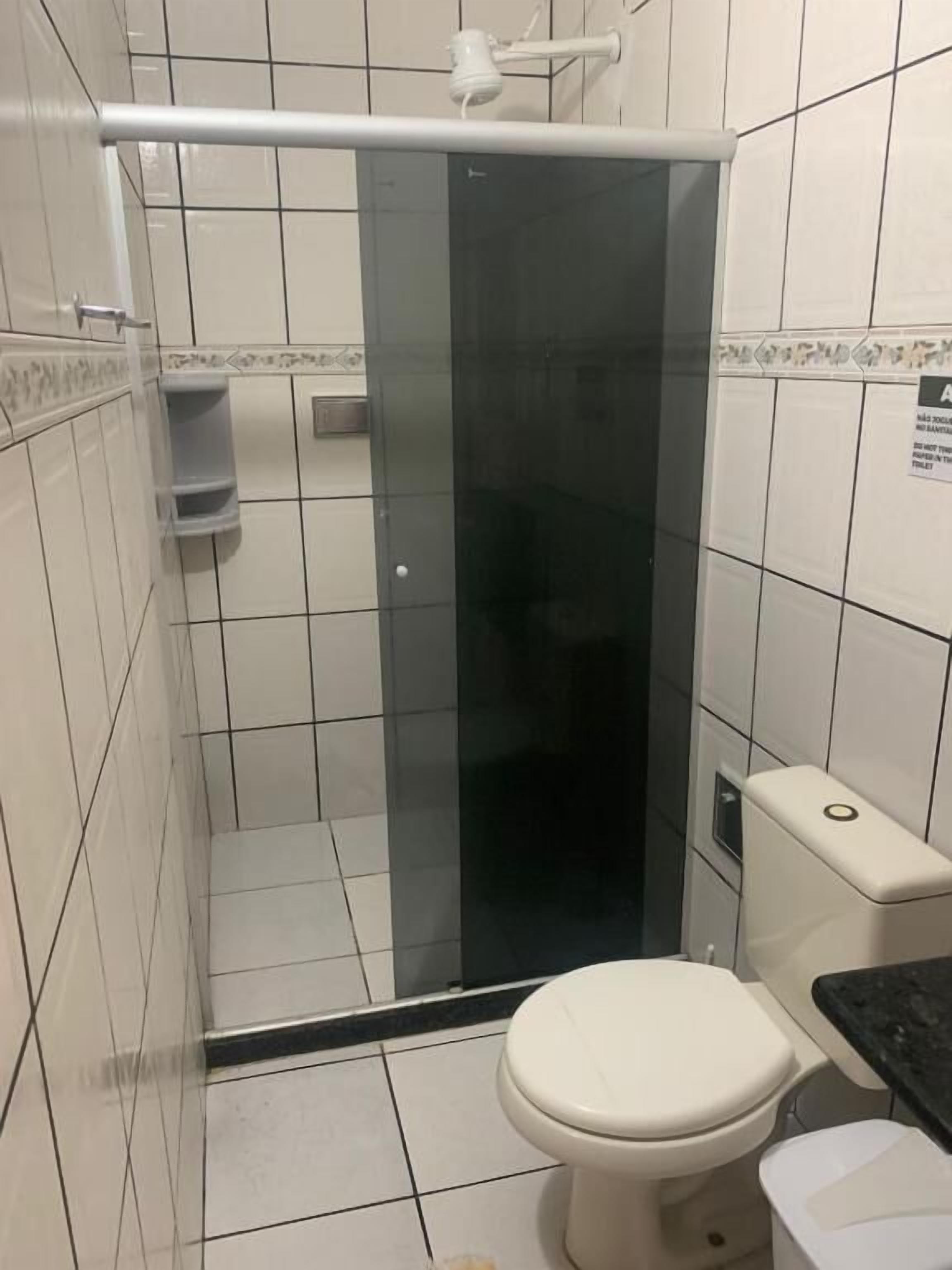 A bathroom with a glass-enclosed shower, a toilet, and a sink.