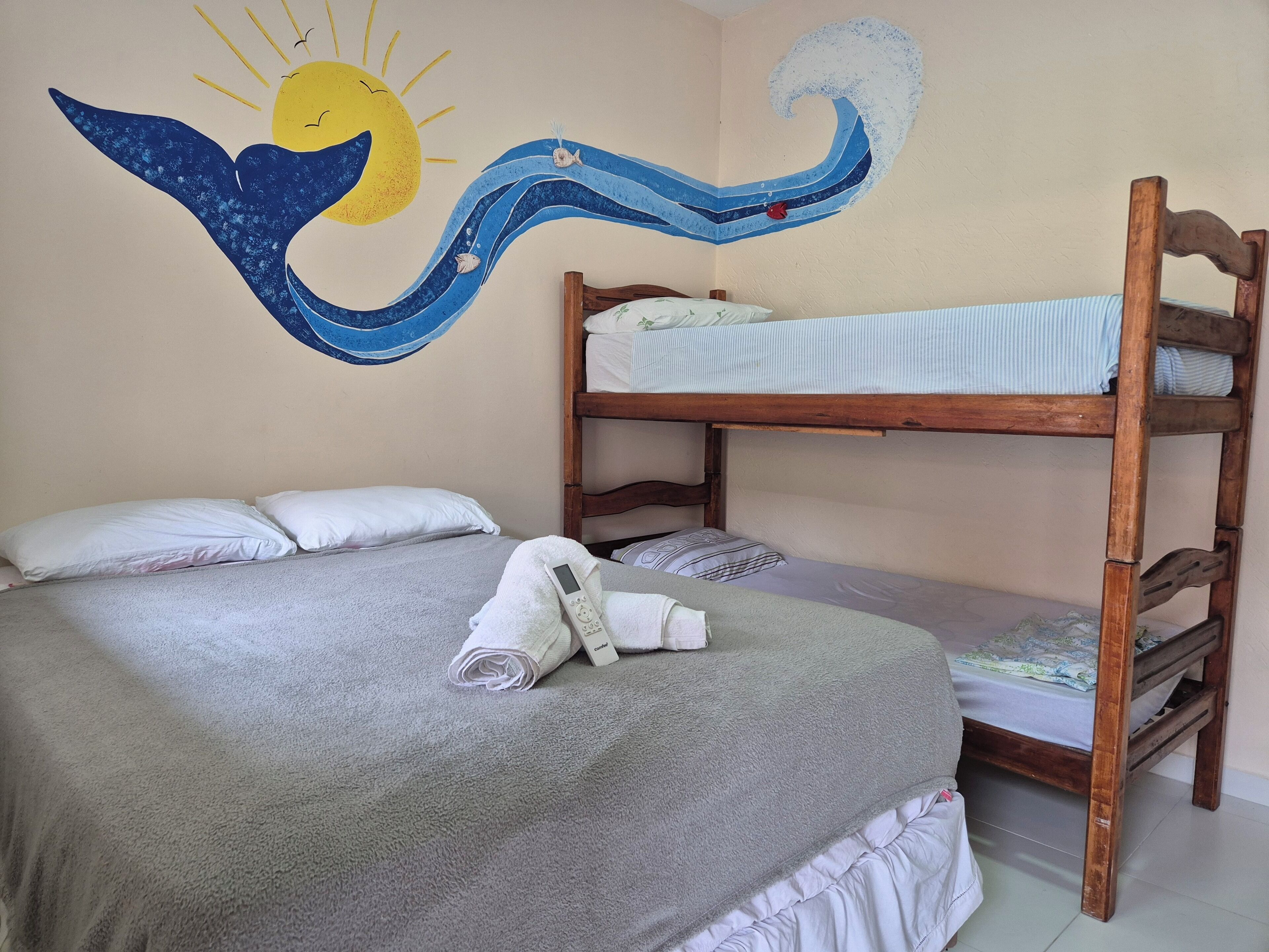 A bunk bed room with a towel on the lower bunk and a wall mural of a sun and wave.