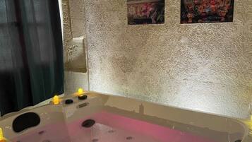 A spa area with a large bathtub, decorative wall panels, and candles.