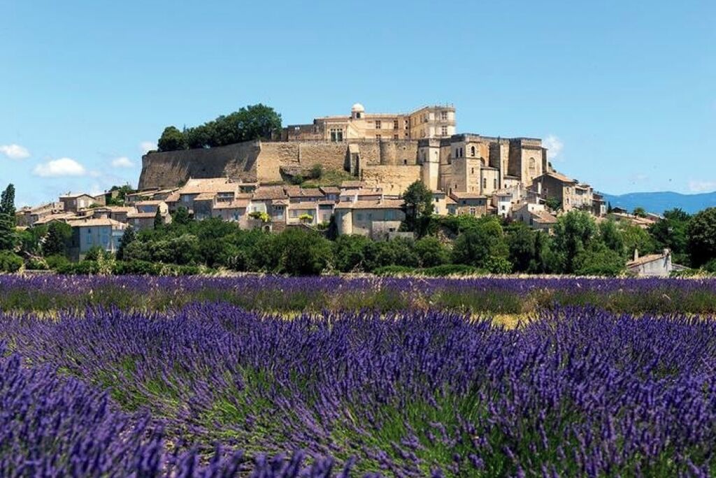 A historic building with a fortified structure, surrounded by a field of lavender.