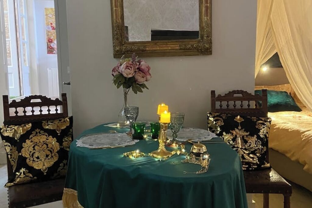 Een eettafel gedekt met een groene tafelkleed, een gouden kandelaar en een bloevas.