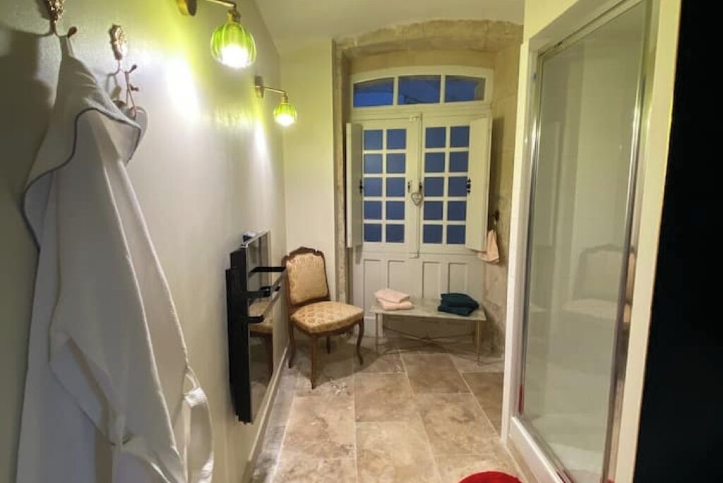 A hallway with a chair, a bench, and a door leading to a room.