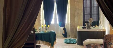 A room with a dining table set for four, a sofa, and a small table with candles.