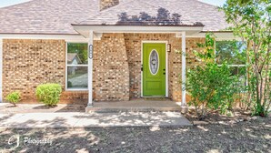 A brick house with a green door, a small porch, and a chimney. - Rex Ranch is a comfortable conveniently located 3 bedroom 2 bath home. (Abilene)
