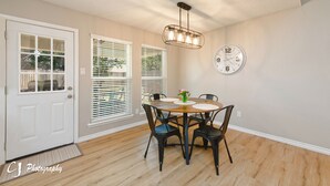 A dining area with a round table, four chairs, a chandelier, a clock, and a door with glass panels. - Rex Ranch is a comfortable conveniently located 3 bedroom 2 bath home. (Abilene)