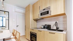 A compact kitchen with wooden cabinets, a built-in oven, a microwave, a sink, and a toaster. - A Sophisticated 2-BR/2BA - Montorgueil (Paris)
