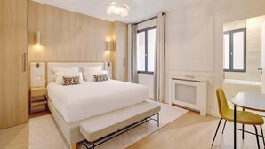 A modern bedroom with a large bed, bedside tables, a small table, and a chair. - A Sophisticated 2-BR/2BA - Montorgueil (Paris)