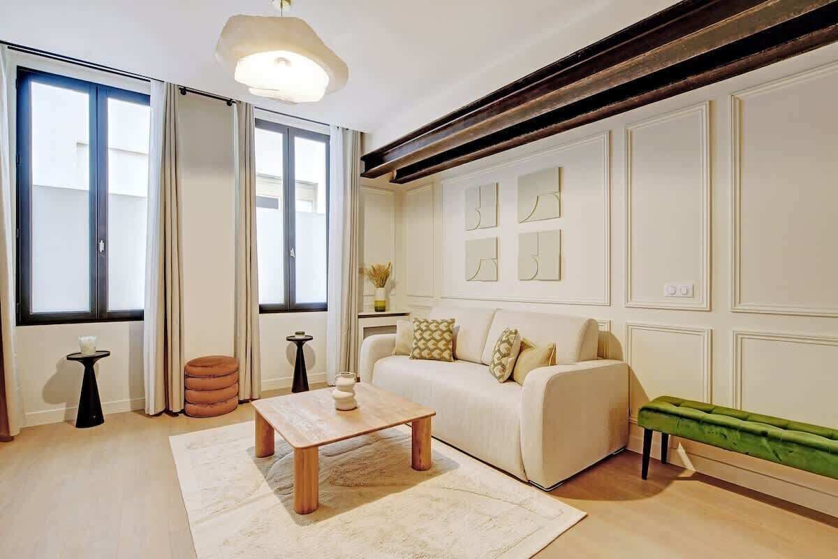 A modern living room with a sofa, a coffee table, a bench, and a large window.