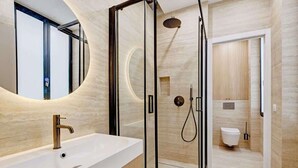 A modern bathroom with a glass-enclosed shower, a standalone sink, and a toilet. - A Sophisticated 2-BR/2BA - Montorgueil (Paris)