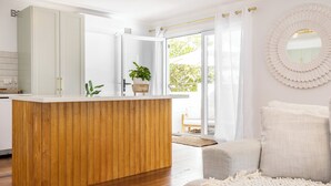 A modern kitchen with a wooden island, white cabinets, and a potted plant. - Cove Cottage South West Rocks (South West Rocks)