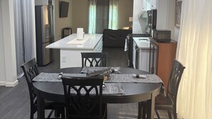 Une cuisine moderne avec un coin repas, comprenant un îlot central, des chaises en bois foncé et une grande table.