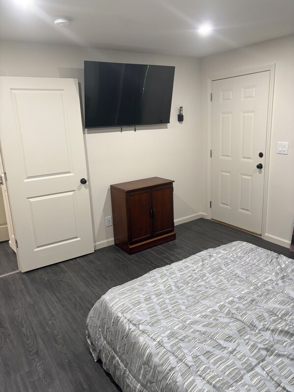 A bedroom with a bed, a wardrobe, a television mounted on the wall, and a door.