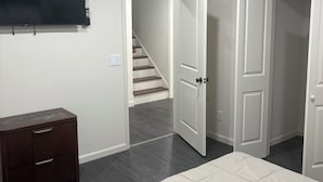 Une chambre à coucher comprenant un lit, une commode, un téléviseur et un escalier menant à une autre pièce.
