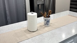 Une cuisine dotée d’un plan de travail en marbre, d’un réfrigérateur en acier inoxydable, d’un porte-rouleau en papier et d’un vase contenant des ustensiles.