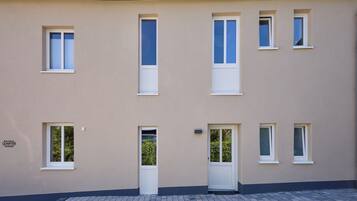 A building with multiple windows and a door, a tiled ground, and a sign indicating 'QUARTIER PIESPORT'.
