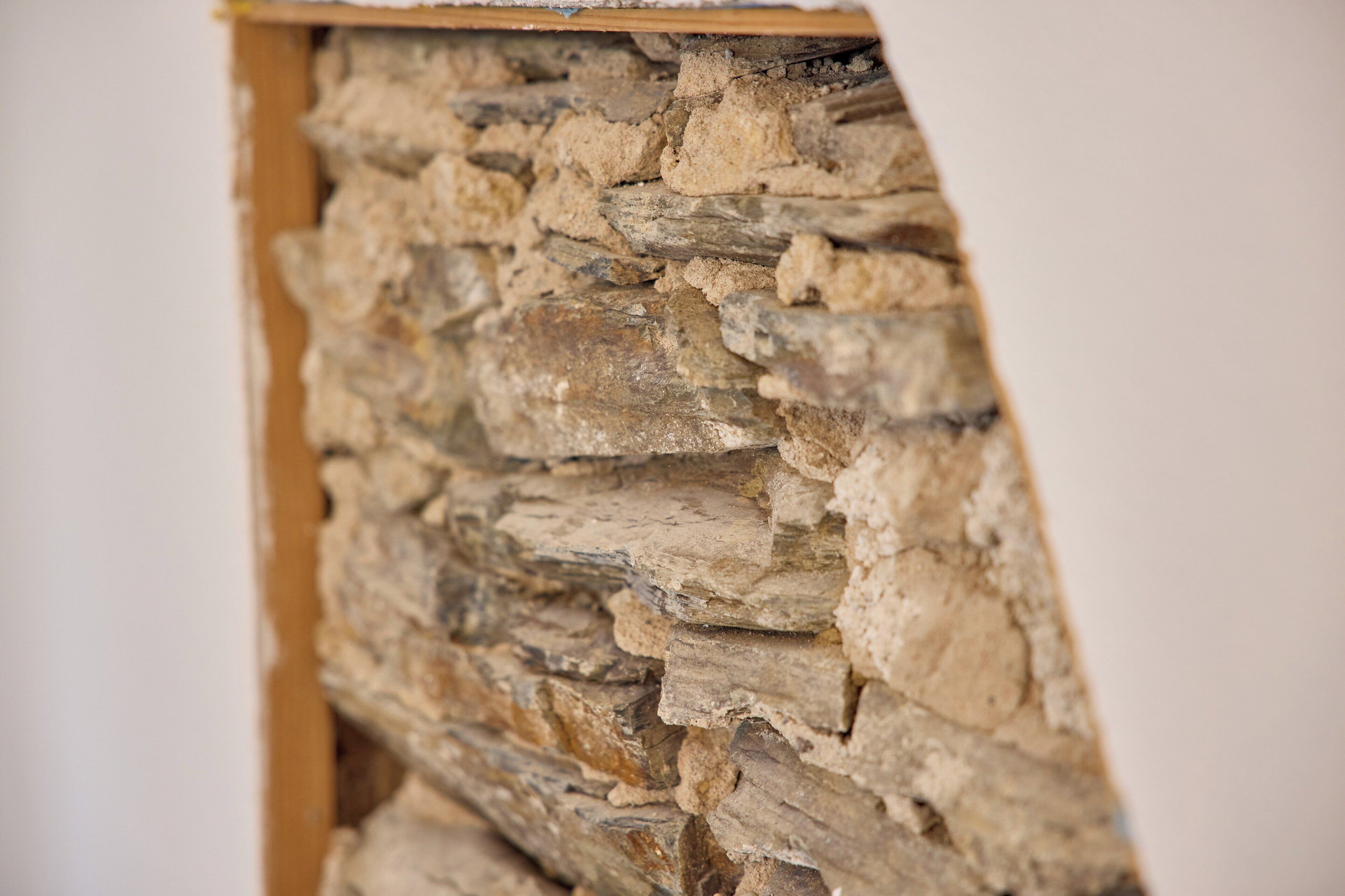 Nahaufnahme einer Steinmauer aus unregelmäßig geformten Steinen, die horizontal gestapelt sind.