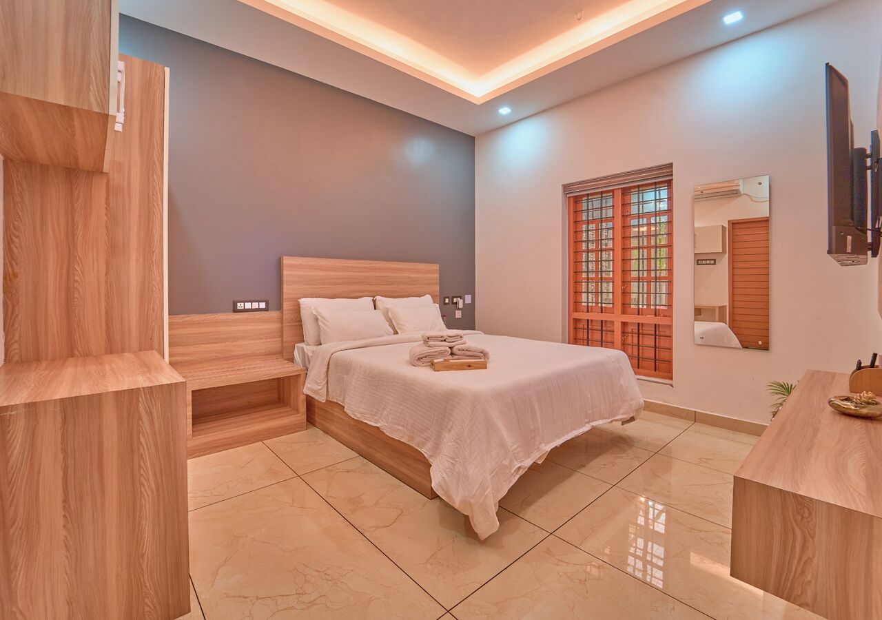 A modern bedroom with a wooden bed, a nightstand, a bedside table, and a TV mounted on the wall.