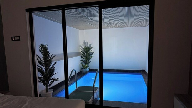 A room with a large sliding glass door leading to a swimming pool area. - Sarang Resort Varkala by VOYE HOMES (Varkala)