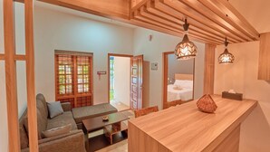 A modern interior with a wooden ceiling, a sofa, a dining table, and a kitchen area. - Sarang Resort Varkala by VOYE HOMES (Varkala)