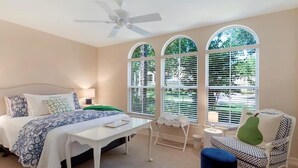 A bedroom with a bed, a desk, a chair, and a window with blinds.